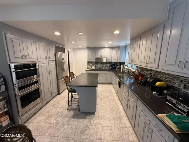 a kitchen with kitchen island granite countertop a stove refrigerator and cabinets