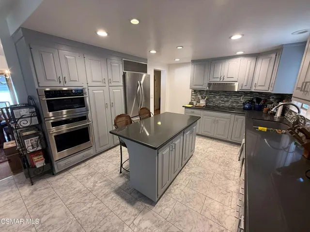 a kitchen with stainless steel appliances granite countertop a stove top oven a sink and a refrigerator