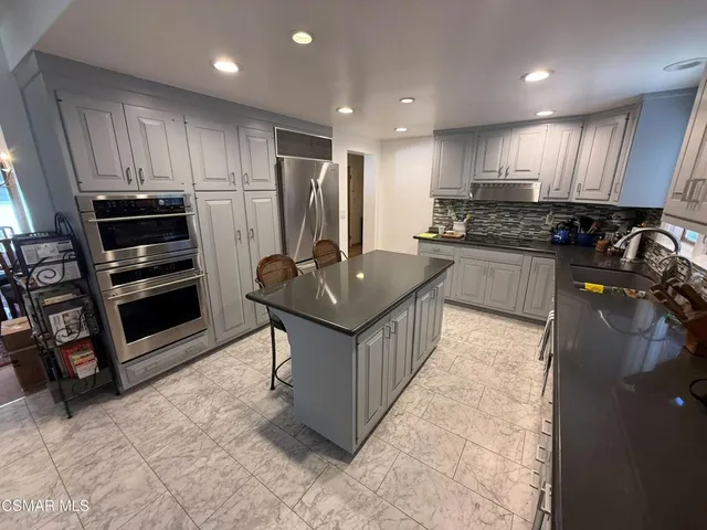 a kitchen with stainless steel appliances granite countertop a stove a refrigerator a sink and a microwave