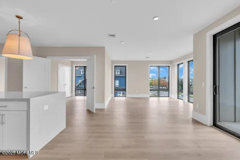 a view of an empty room with wooden floor and a fireplace