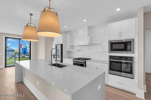 a kitchen with stainless steel appliances granite countertop a sink a stove and a wooden floors