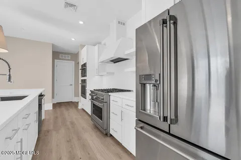 a kitchen with stainless steel appliances granite countertop a refrigerator a sink and white cabinets