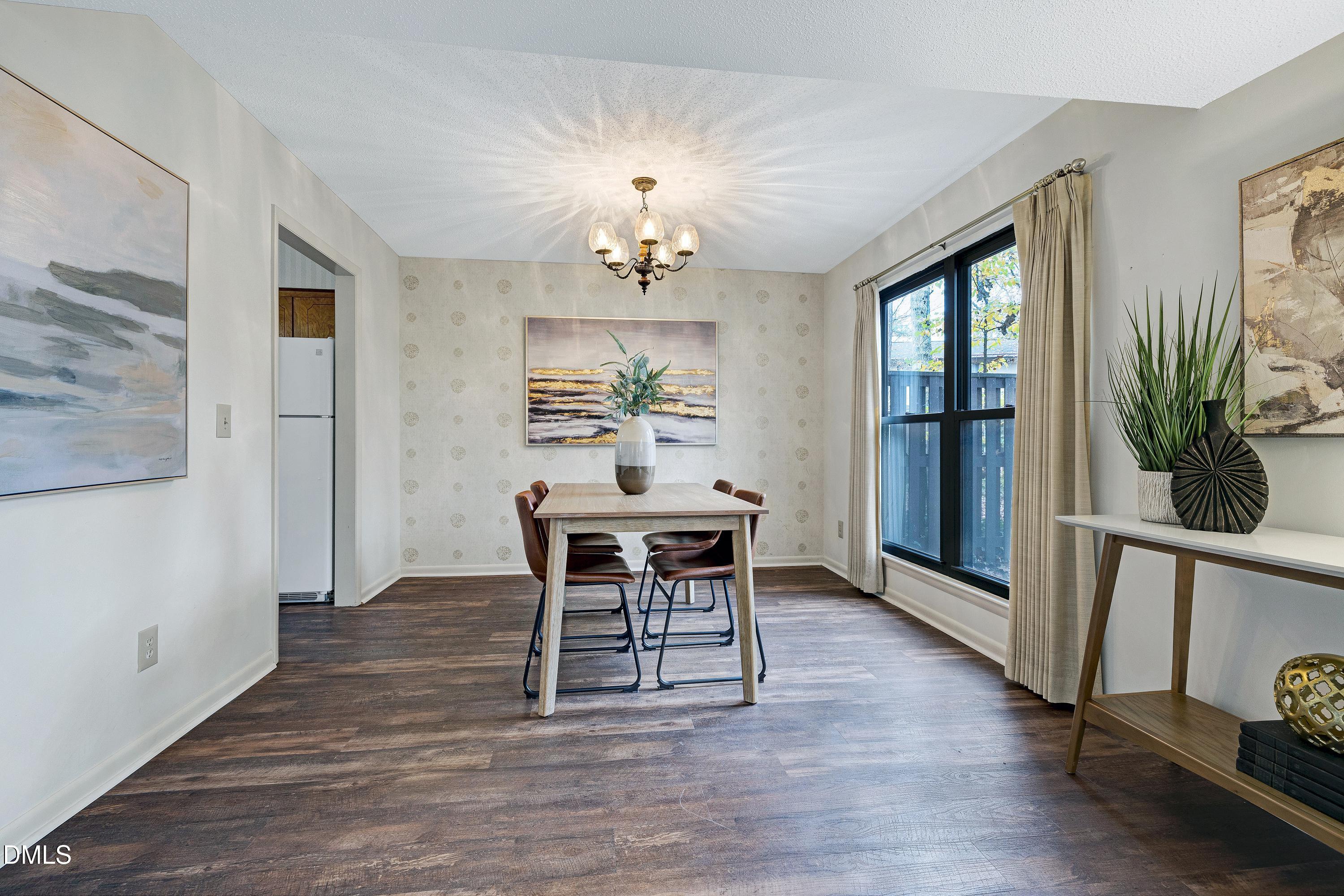 3905 Wendy Lane Raleigh, NC 27606 - Photo 8 of 42 a dining room with wooden floor a chandelier a wooden table and chairs