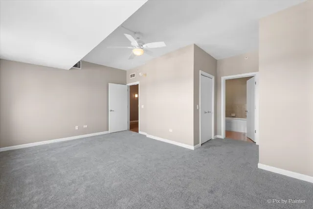 an empty room with chandelier fan and windows