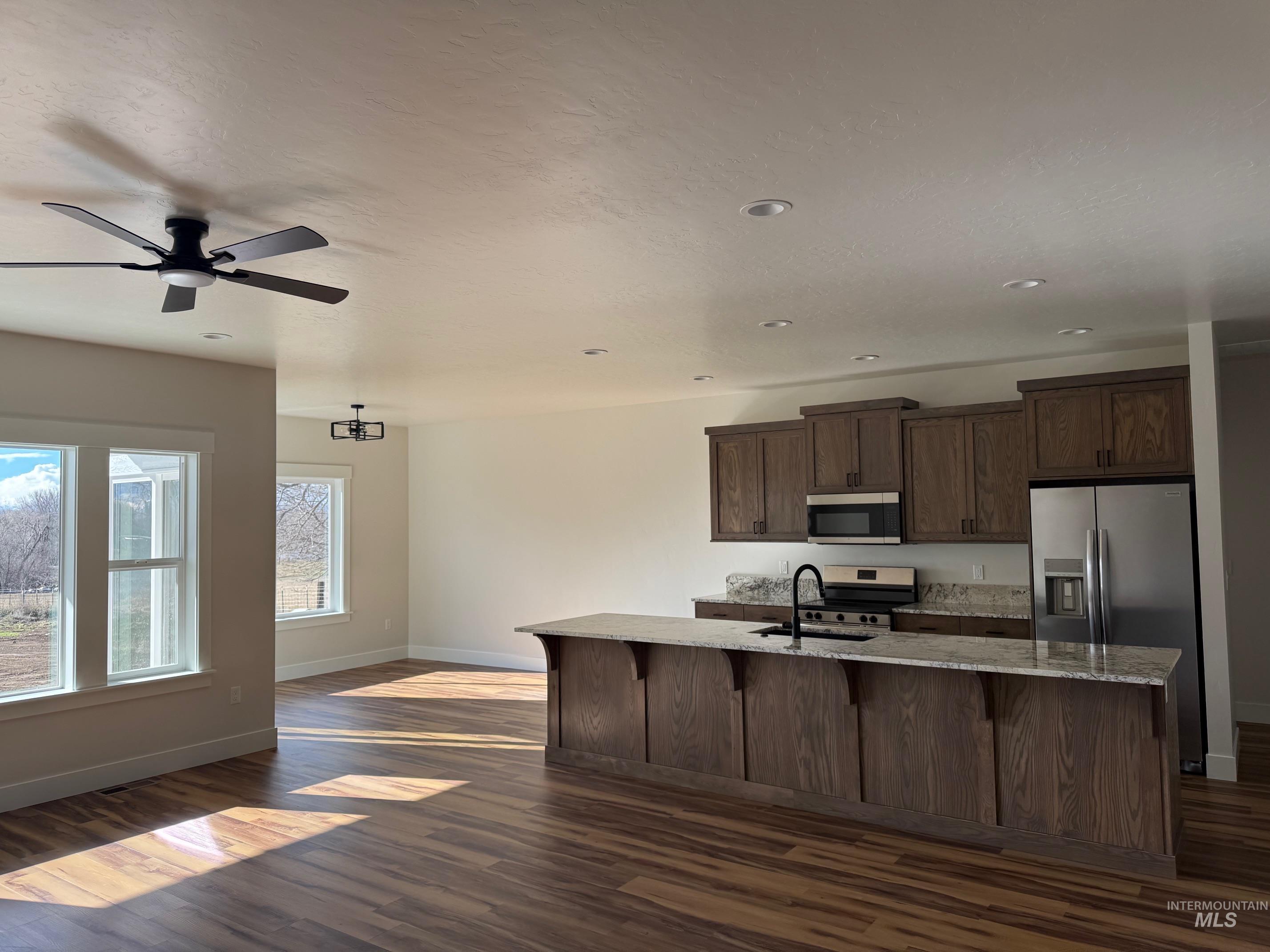 1705 Ruth Lane Nampa, ID 83686 - Photo 2 of 2 Kitchen with a center island with sink, stainless steel appliances, light stone countertops, dark wood finished floors, and open floor plan