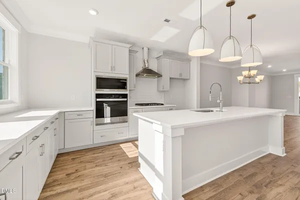 a large kitchen with a lot of white cabinets and stainless steel appliances