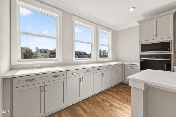 a kitchen with white cabinets appliances and a window