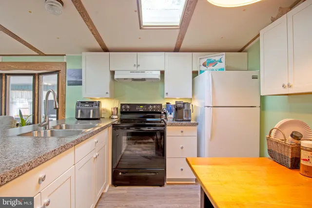 a kitchen with stainless steel appliances granite countertop a refrigerator a stove a sink dishwasher and white cabinets with wooden floor