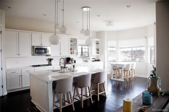 a kitchen with stainless steel appliances a dining table chairs stove and white cabinets