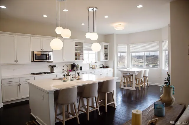 a kitchen with a dining table chairs sink and white cabinets