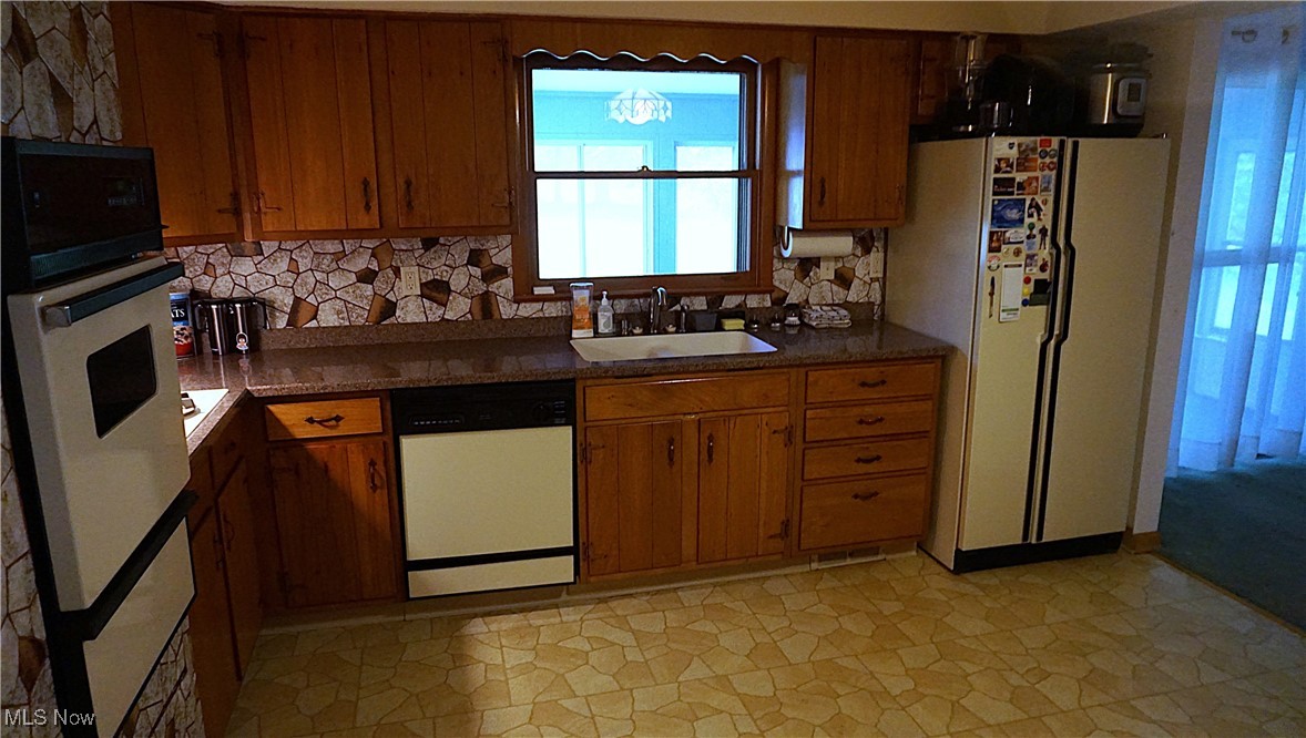 2100 West Pleasant Valley Road Cleveland, OH 44134 - Photo 10 of 30 Kitchen with white appliances, a sink, brown cabinetry, and decorative backsplash