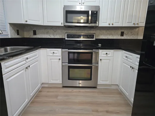 a kitchen with granite countertop white cabinets and stainless steel appliances