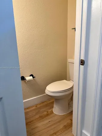 a bathroom with a toilet and a wooden floor