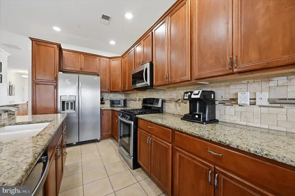 a kitchen with stainless steel appliances granite countertop a sink a stove and a refrigerator