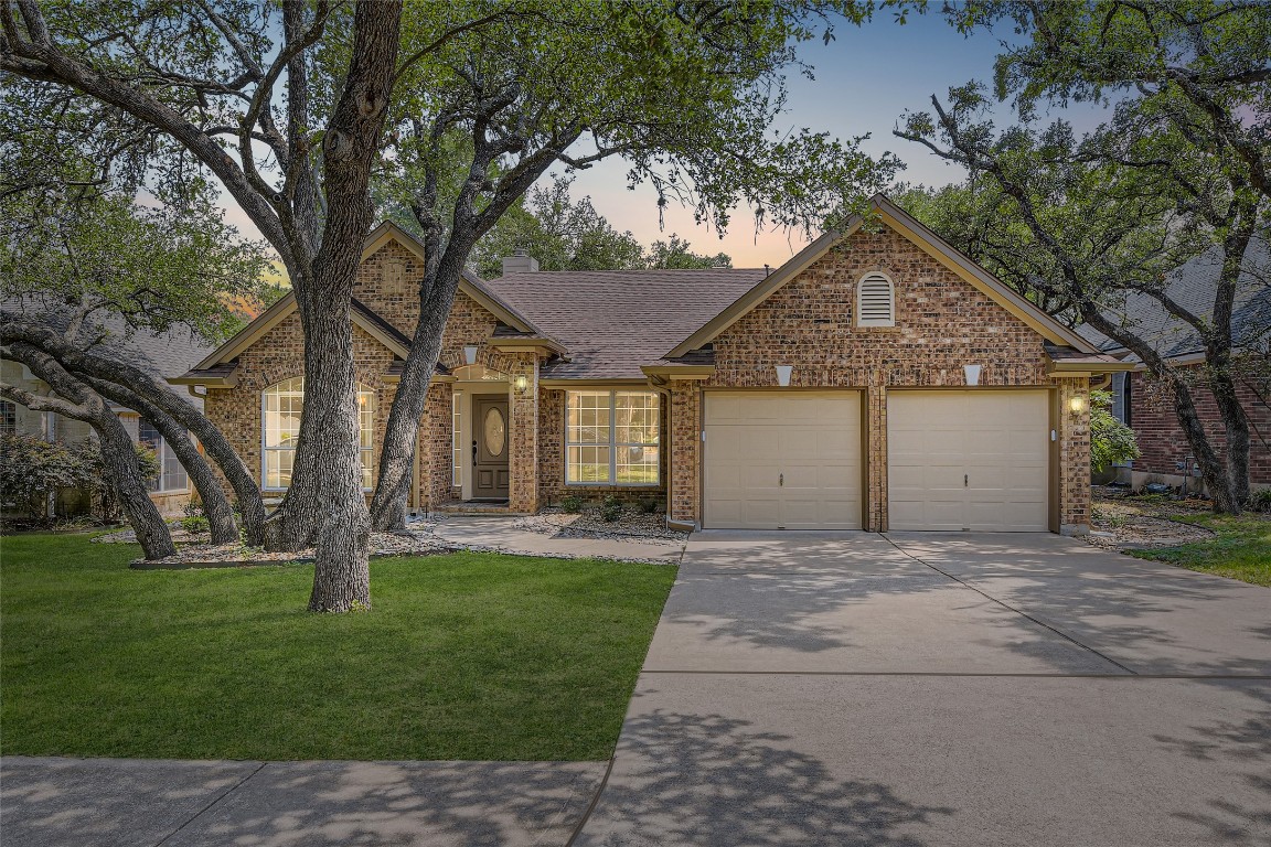 a front view of a house with a garden and trees