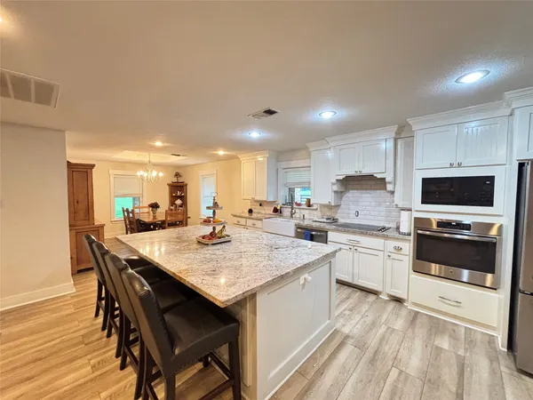 a kitchen with stainless steel appliances kitchen island granite countertop a table chairs sink and cabinets