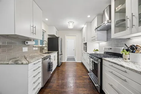 a large kitchen with stainless steel appliances kitchen island granite countertop a stove a sink dishwasher and a refrigerator