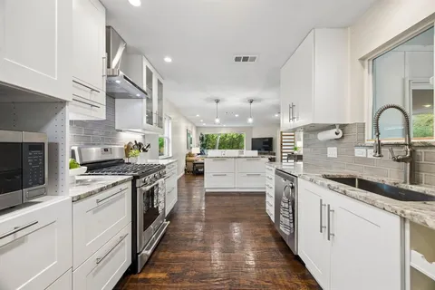 a kitchen with stainless steel appliances granite countertop lots of white cabinets a sink and dishwasher