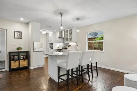 a kitchen with stainless steel appliances a dining table chairs and wooden floor