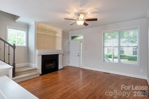 a view of an empty room with wooden floor fireplace and a window