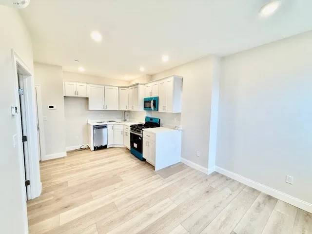 a kitchen with white cabinets and stainless steel appliances