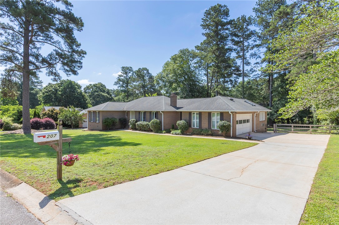 207 Laurel Ridge Road Anderson, SC 29621 - Photo 4 of 50 A well-maintained ranch-style residence presents a broad concrete driveway leading to the garage, amidst a lush, verdant lawn.