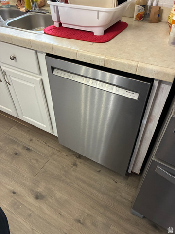 547 East 2000th Street North Vernal, UT 84078 - Photo 6 of 50 Stainless steel dishwasher integrated into white cabinetry with a tiled countertop and wood-finish flooring