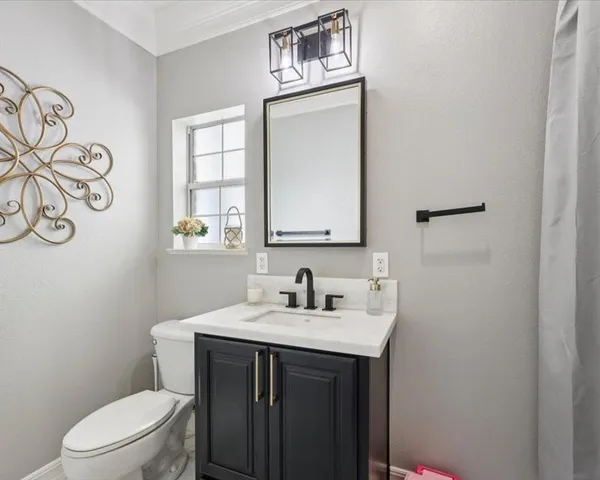 a bathroom with a sink vanity mirror and toilet
