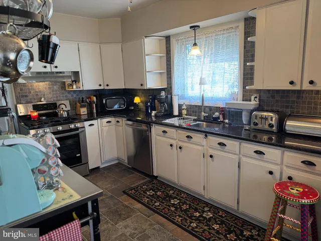 a kitchen with granite countertop a sink a stove and cabinets