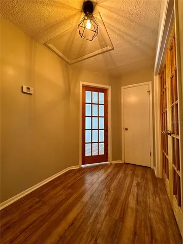 a view of an empty room with wooden floor and a window