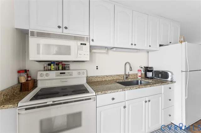 a kitchen with granite countertop white cabinets and white appliances
