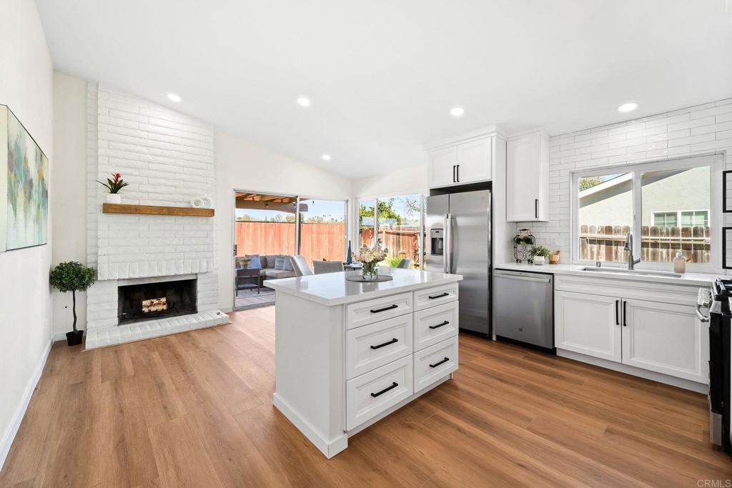 5055 Andrew Jackson Street Oceanside, CA 92057 - Photo 13 of 43 a large kitchen with granite countertop a stove top oven a sink dishwasher and a fireplace with wooden floor