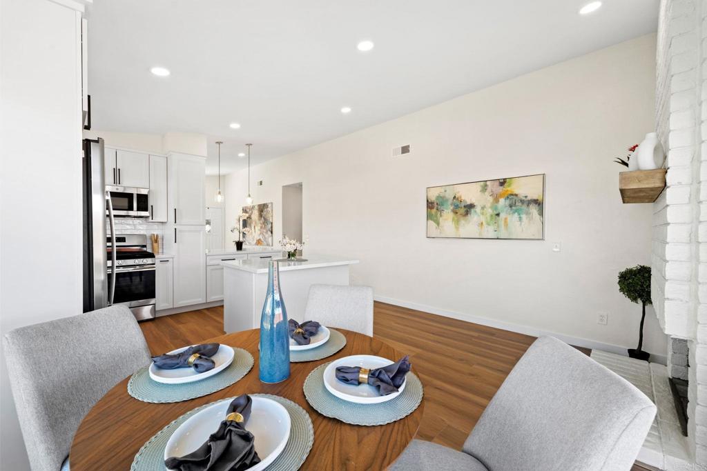 5055 Andrew Jackson Street Oceanside, CA 92057 - Photo 18 of 43 a kitchen with stainless steel appliances kitchen island granite countertop a dining table and chairs with wooden floor