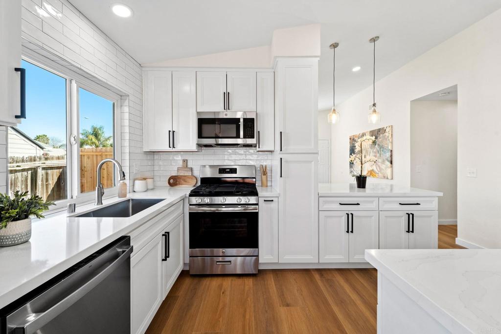 5055 Andrew Jackson Street Oceanside, CA 92057 - Photo 9 of 43 a kitchen with stainless steel appliances white cabinets a sink a stove a refrigerator and microwave