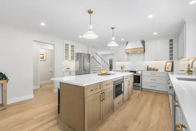 a kitchen with stove a sink dishwasher and a refrigerator with wooden floor