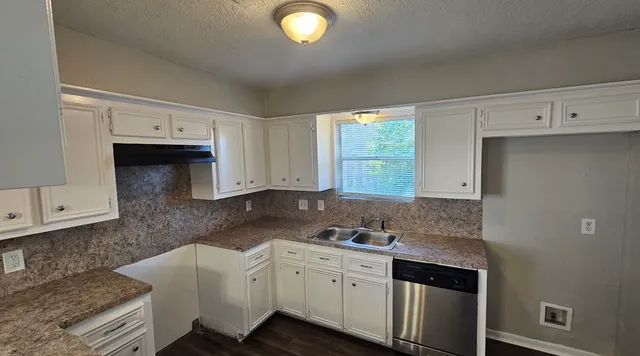a kitchen with granite countertop a sink a stove and cabinets