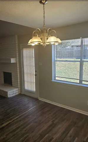 a view of a room with wooden floor chandelier and fireplace