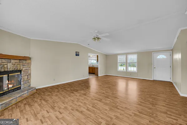 a view of an empty room with window and wooden floor