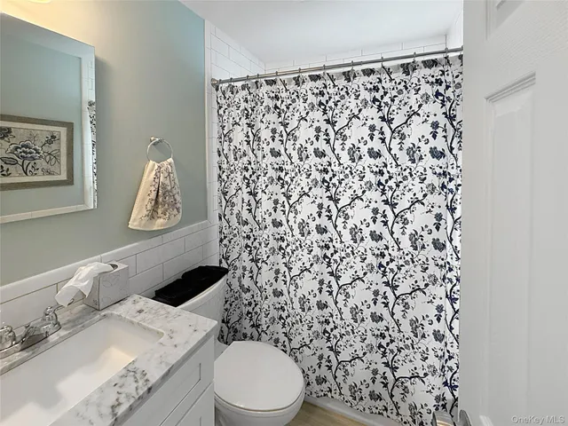 a bathroom with a granite countertop toilet and a sink