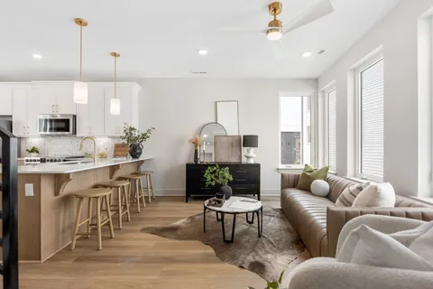 a living room with furniture kitchen view and a wooden floor