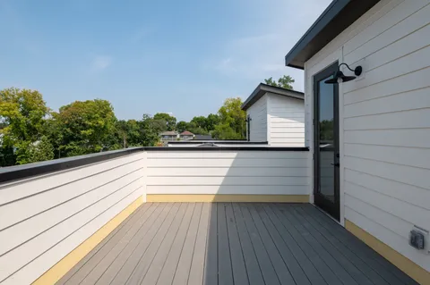 a view of balcony and deck with wooden floor and fence and a floor to ceiling window