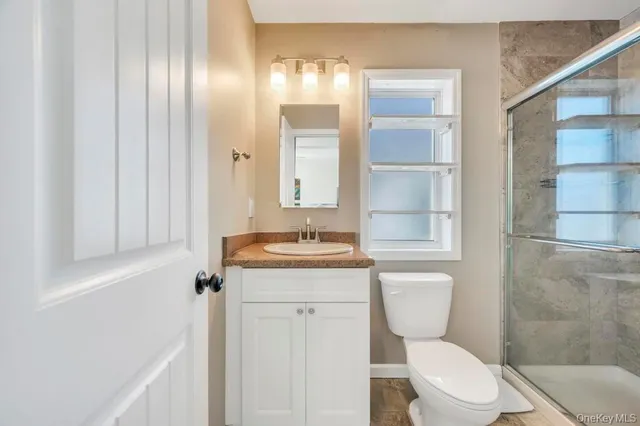 a bathroom with a granite countertop toilet a sink and a mirror