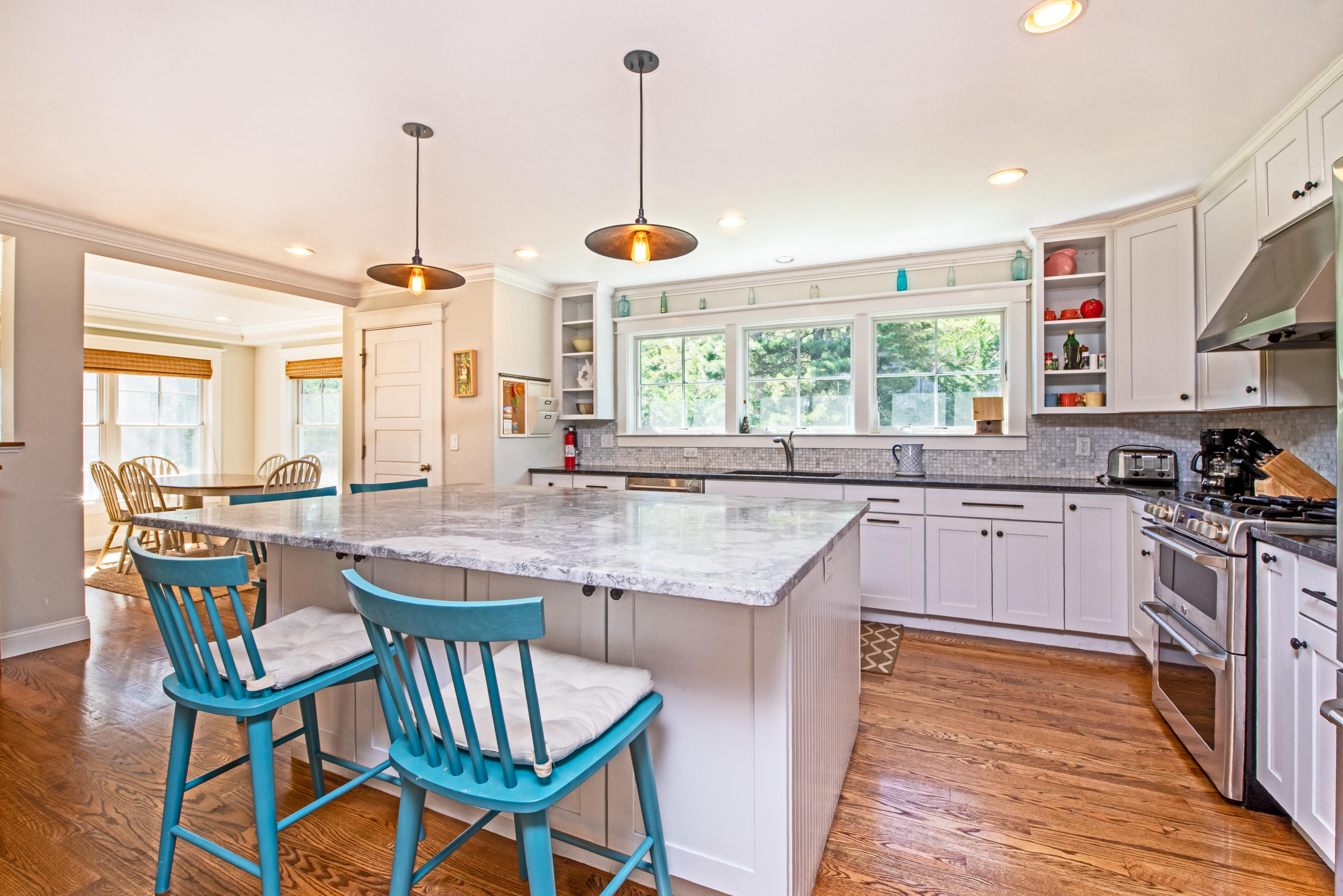100 Peace Valley Road Wellfleet, MA 02667 - Photo 12 of 33 a kitchen with stainless steel appliances granite countertop a stove top oven a sink a dining table and chairs with wooden floor