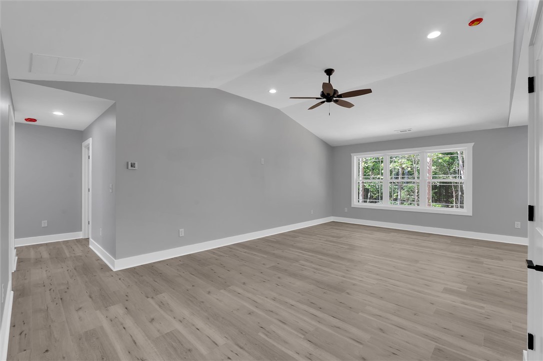 An airy bedroom with vaulted ceilings and ample natural light from large windows overlooking green foliage.