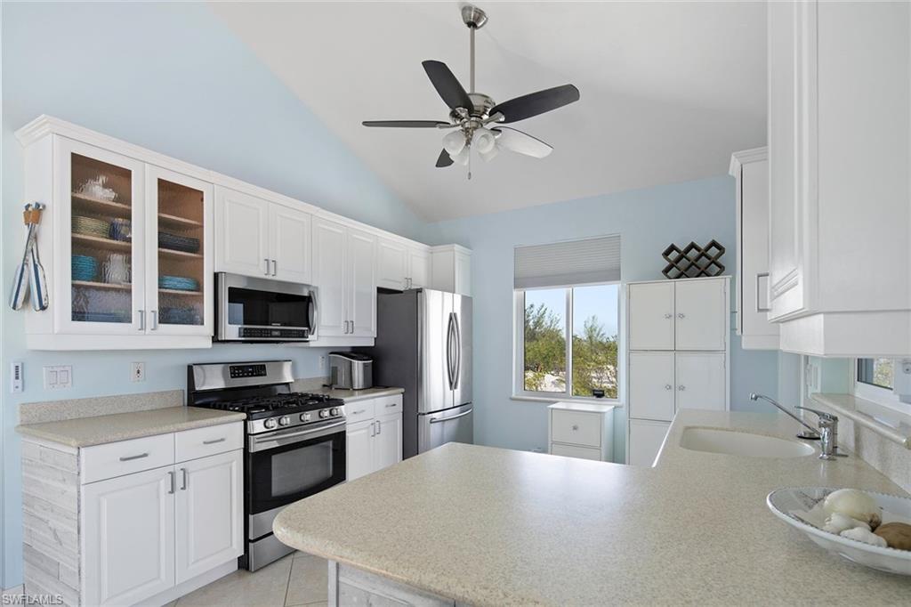 11687 Keewaydin Naples, FL 34113 - Photo 18 of 49 a kitchen with stainless steel appliances kitchen island granite countertop a stove a sink and a refrigerator