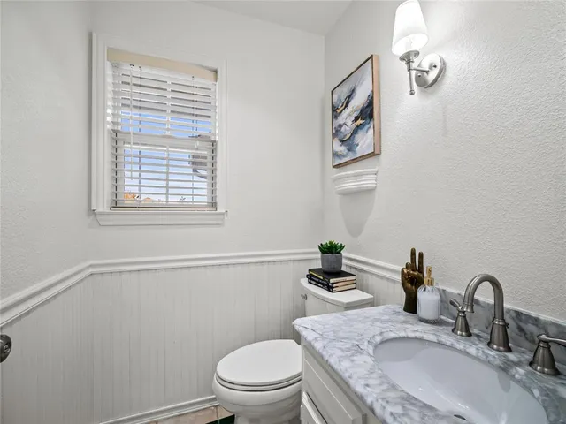 a bathroom with a granite countertop toilet a sink and a mirror