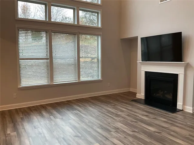 a view of an empty room with wooden floor fireplace and a window