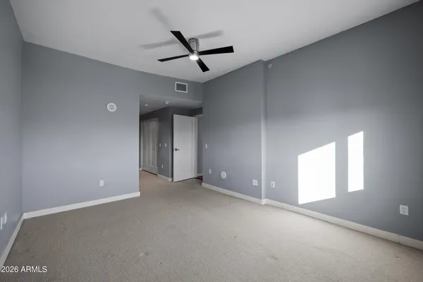 an empty room with a ceiling fan and window