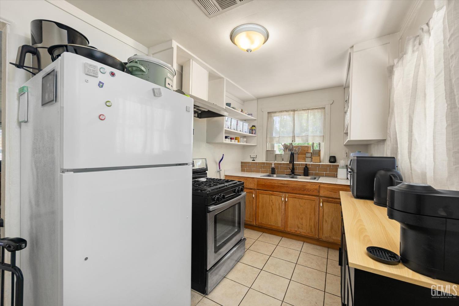 Undisclosed Address Bakersfield, CA 93304 - Photo 16 of 25 a kitchen with granite countertop a refrigerator a sink a stove and white cabinets