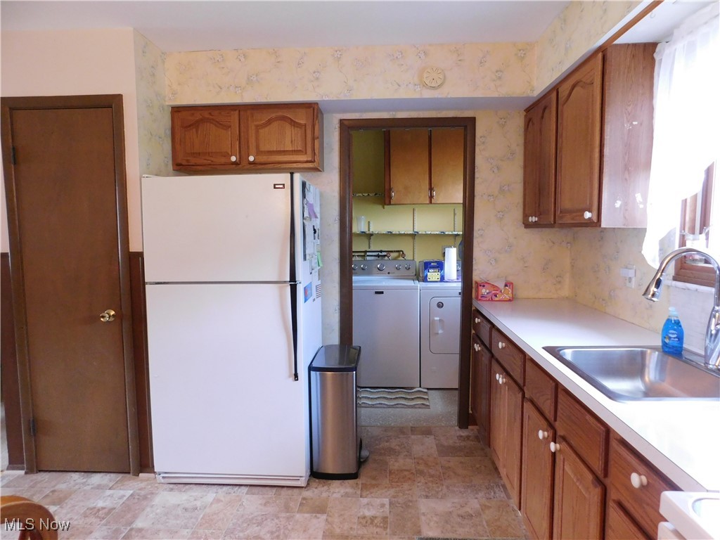 9255 Root Road North Ridgeville, OH 44039 - Photo 15 of 46 Kitchen featuring washing machine and dryer, light countertops, freestanding refrigerator, brown cabinets, and a sink
